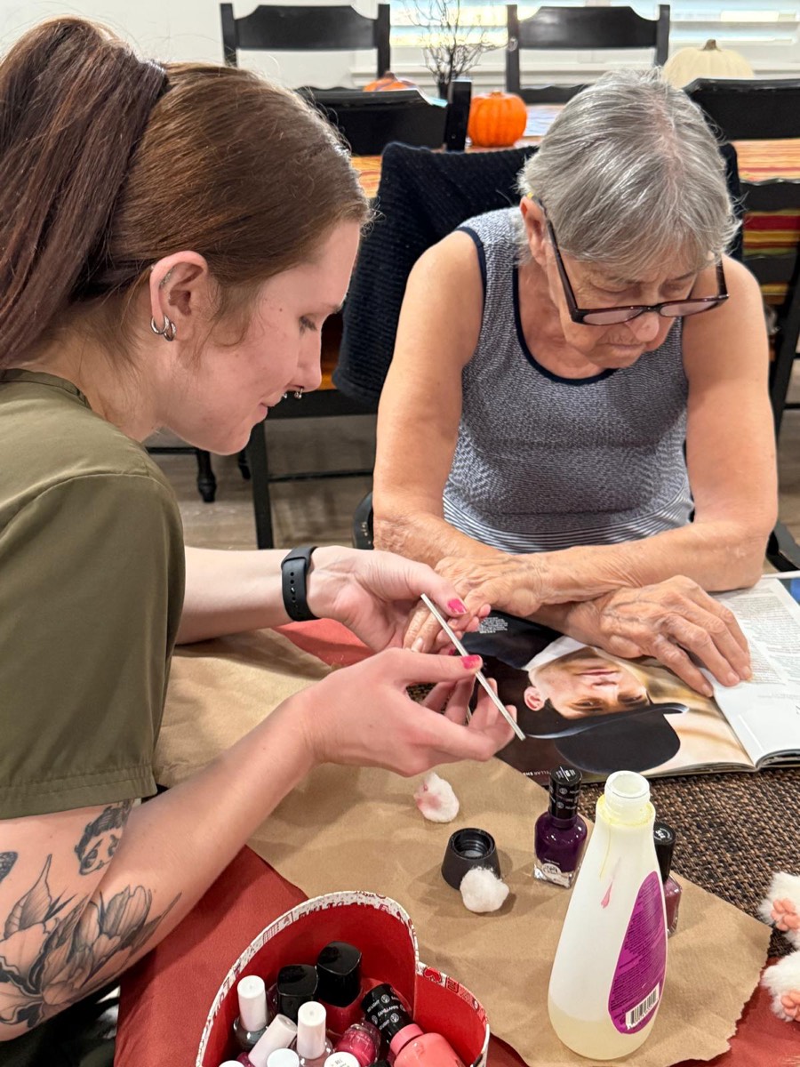 A caregiver giving a resident a manicure at The Gardens