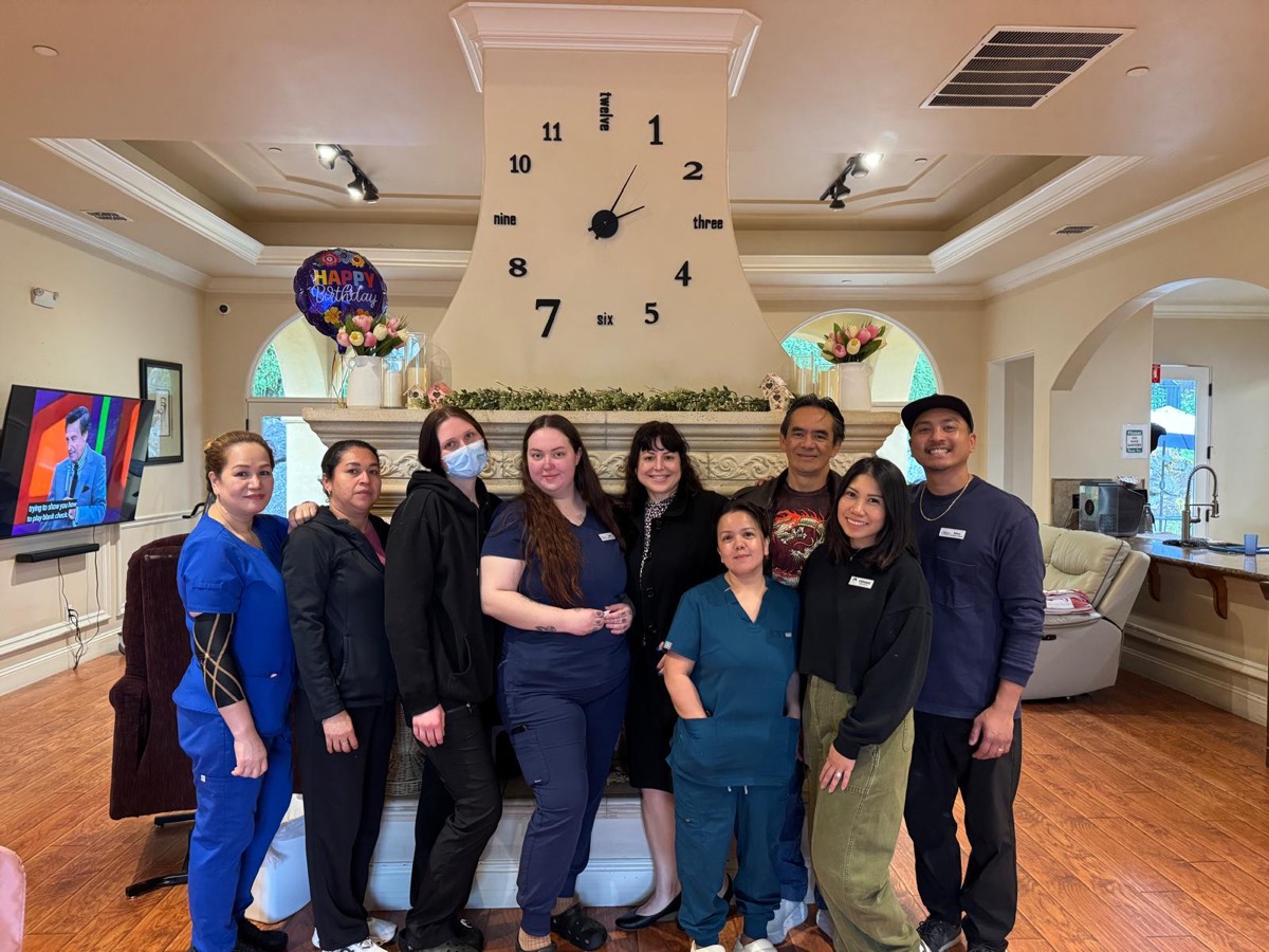 The Villa care team in front of the living room fireplace